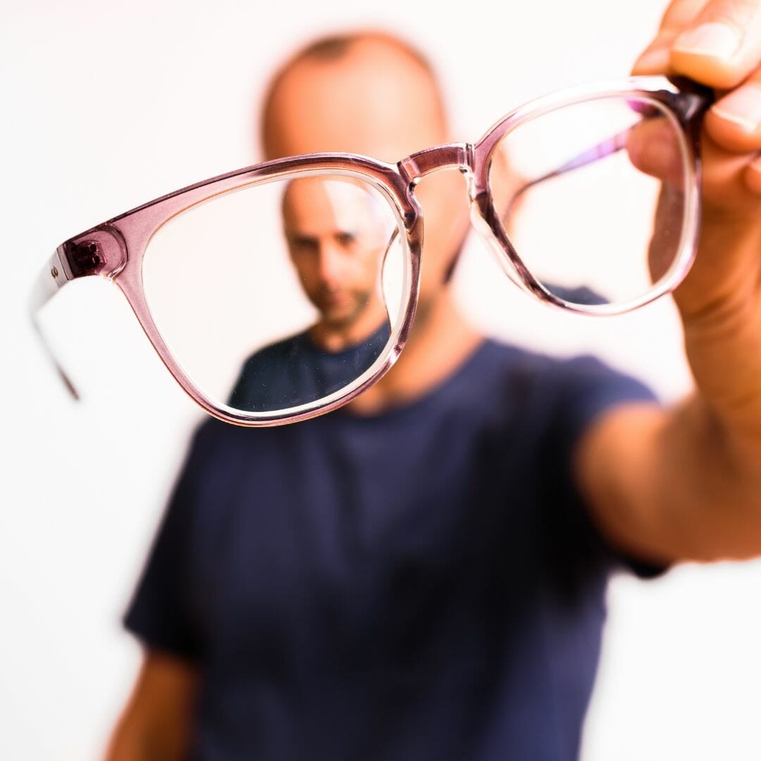 Man holding up eyeglasses with clear eyewear frame