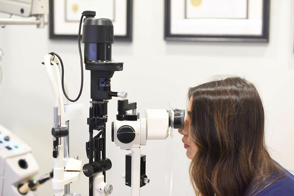 Woman peering into eye exam equipment